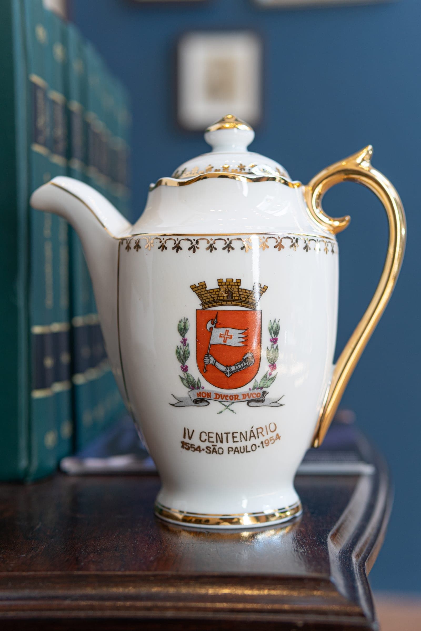 Bule comemorativo com o brasão de São Paulo — porcelana de uso cotidiano transformada em objeto de memória.
