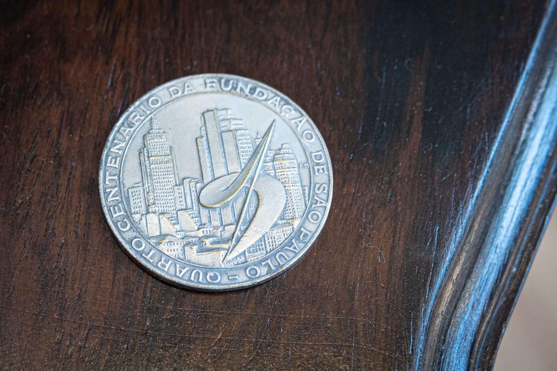 Moeda Comemorativa — A Voluta de Niemeyer em uma das faces, o brasão de São Paulo com três torres na outra.